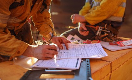 Image: Adobe Close up of mine worker in high vis writing on a piece of paper
